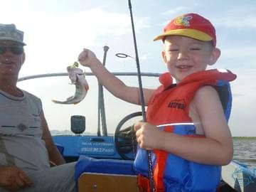Мальчик с удочкой и рыбой на катере